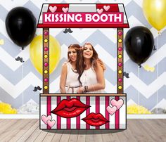 two women standing in front of a booth with balloons