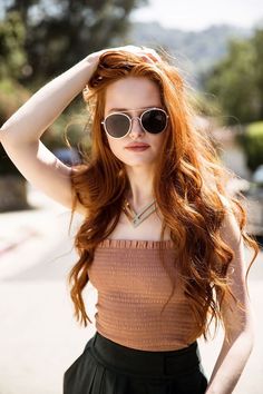 a woman with long red hair wearing sunglasses