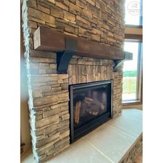 a stone fireplace in a living room next to a window