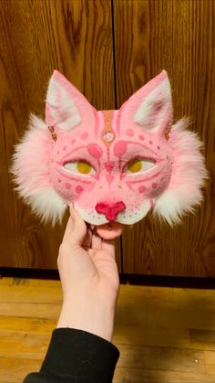 someone is holding up a pink cat mask