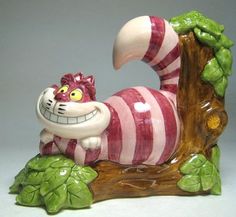 a ceramic cat figurine sitting on top of a tree branch