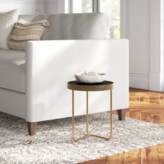 a white couch sitting next to a table on top of a rug