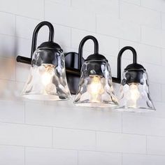 three lights are hanging on the wall next to each other in a bathroom area with white tile walls