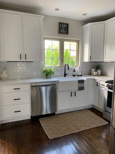 a clean kitchen with white cabinets and stainless steel dishwasher in the center area