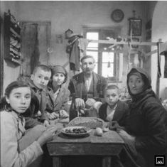 a group of people sitting around a table with food in front of them on it