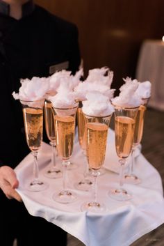 champagne glasses filled with whipped cream sit on a white table cloth, ready to be served