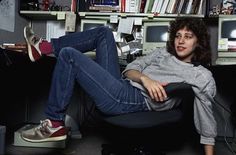 a black and white photo of a woman sitting in an office chair with her legs crossed