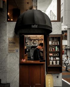 a man standing behind a counter in front of a restaurant with an umbrella over it