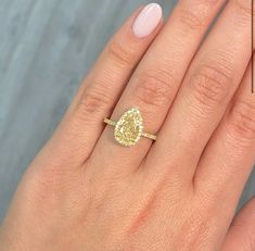 a woman's hand with a yellow diamond ring on top of her left hand