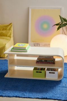 a white table with books on it in a room next to a blue rug and yellow chair