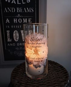 a lit candle sitting on top of a wicker table next to a framed sign