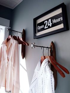 two shirts are hanging on the wall next to a sign that says open 24 hours