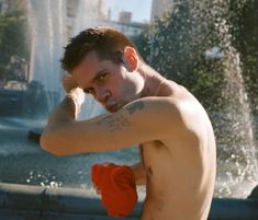 a man with no shirt standing in front of a fountain