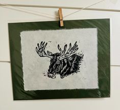 a black and white drawing of a moose's head hanging from a clothes line