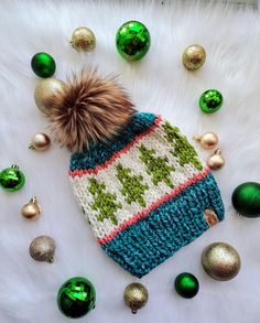 a knitted hat with a pom - pom on top surrounded by christmas ornaments