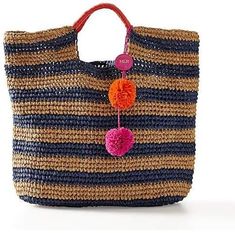 a multicolored straw bag with pom - poms hanging from the handle