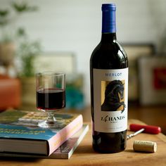 a bottle of wine next to a glass and book