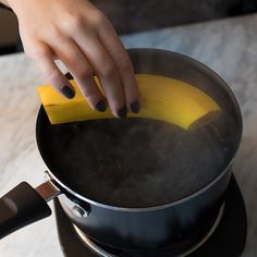 a person using a sponge to clean the bottom of a frying pan on a stove