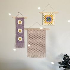 two crocheted wall hangings with flowers on them, one is purple and the other is yellow