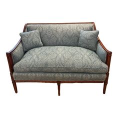 an upholstered couch with two pillows on it's back and arms, against a white background