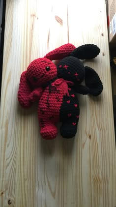 two black and red stuffed animals sitting on top of a wooden table