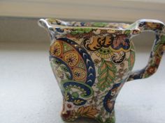 a colorful vase sitting on top of a counter next to a white window sill