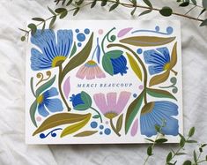 a blue and pink flowered card with the words merri beauoup on it