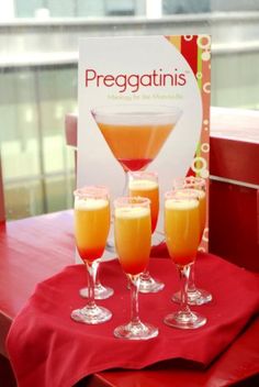 three glasses of orange juice sitting on top of a red table next to a sign