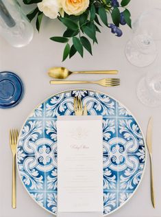 a blue and white plate with a menu on it next to some gold cutlery