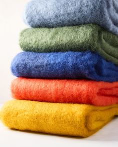 a stack of different colored towels sitting on top of each other in front of a white background