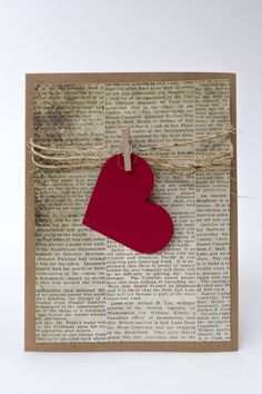 a red heart hanging from a string on top of a piece of paper