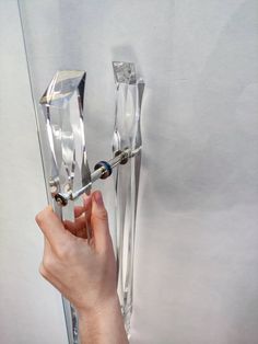 a person holding an object in their hand and pointing it at the door knobs