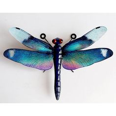 a blue dragonfly sitting on top of a white wall