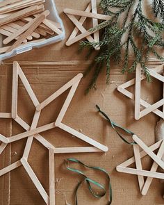 popsicle snowflakes are arranged on a table with pine branches and scissors