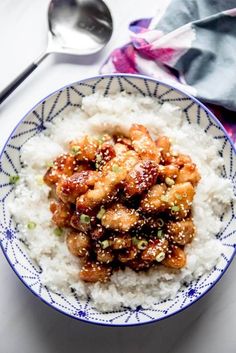 a blue and white bowl filled with rice covered in chicken