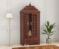 a wooden cabinet sitting on top of a floor next to a lamp and potted plant