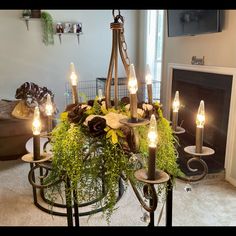 a chandelier with candles and flowers on it in front of a fire place