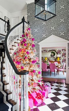 a christmas tree with pink and gold ornaments on it in front of a black and white checkerboard wall