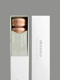 two macaroons in a white box on a gray surface with the lid open