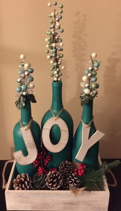 three wine bottles decorated with christmas decorations and the word joy spelled out in white letters