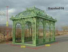 a green metal gazebo sitting on the side of a road next to a field