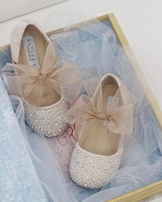 two pairs of shoes in a box with a bow on the front and bottom part