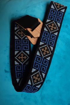 a pair of black and blue knitted ties on a blue background with a wooden clip