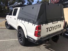 the back end of a white toyota truck parked in a parking lot next to a sign