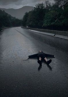 a person laying on the road with an umbrella