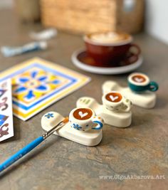 a close up of some type of crafting supplies on a table with a cup of coffee in the background