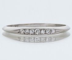 "Here in rich, strong platinum we have a classic antique diamond band. Seven shimmering diamonds sit prettily across the face of this petite band. A bonus is that it is engraved, and we love that in our shop because it allows us to dream of a wonderful romance of long ago. Pair it with your modern or antique engagement ring or wear it on it's own. Antique Wedding Band - Antique Platinum Diamond Wedding Band Platinum 7 Diamonds =.11ct VS/G-H Engraved \"P.H.F. to A.G.? 9.3.31\" Ring Size 8.75 (rin Timeless Wedding Bands With Prong Setting, Formal Diamond Eternity Band With Single Diamond, Classic Bands With Single Cut Diamonds For Promise Ring, Classic Bands With Diamond Accents For Promise Ring, Wedding Diamond Ring With Single Cut Classic Shape, Timeless Wedding Bands With Diamond Accents, Wedding Diamond Ring With Single Cut Diamonds, Classic Eternity Band With Single Cut Diamonds For Promise, Heirloom Diamond Band With Single Cut Diamonds