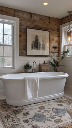 a white bath tub sitting in a bathroom next to two windows and a rug on the floor