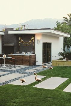 two flamingos standing in front of a house with the words happy weekend written on it