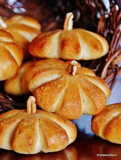 small pumpkin shaped breads sitting on top of a table next to a wicker basket